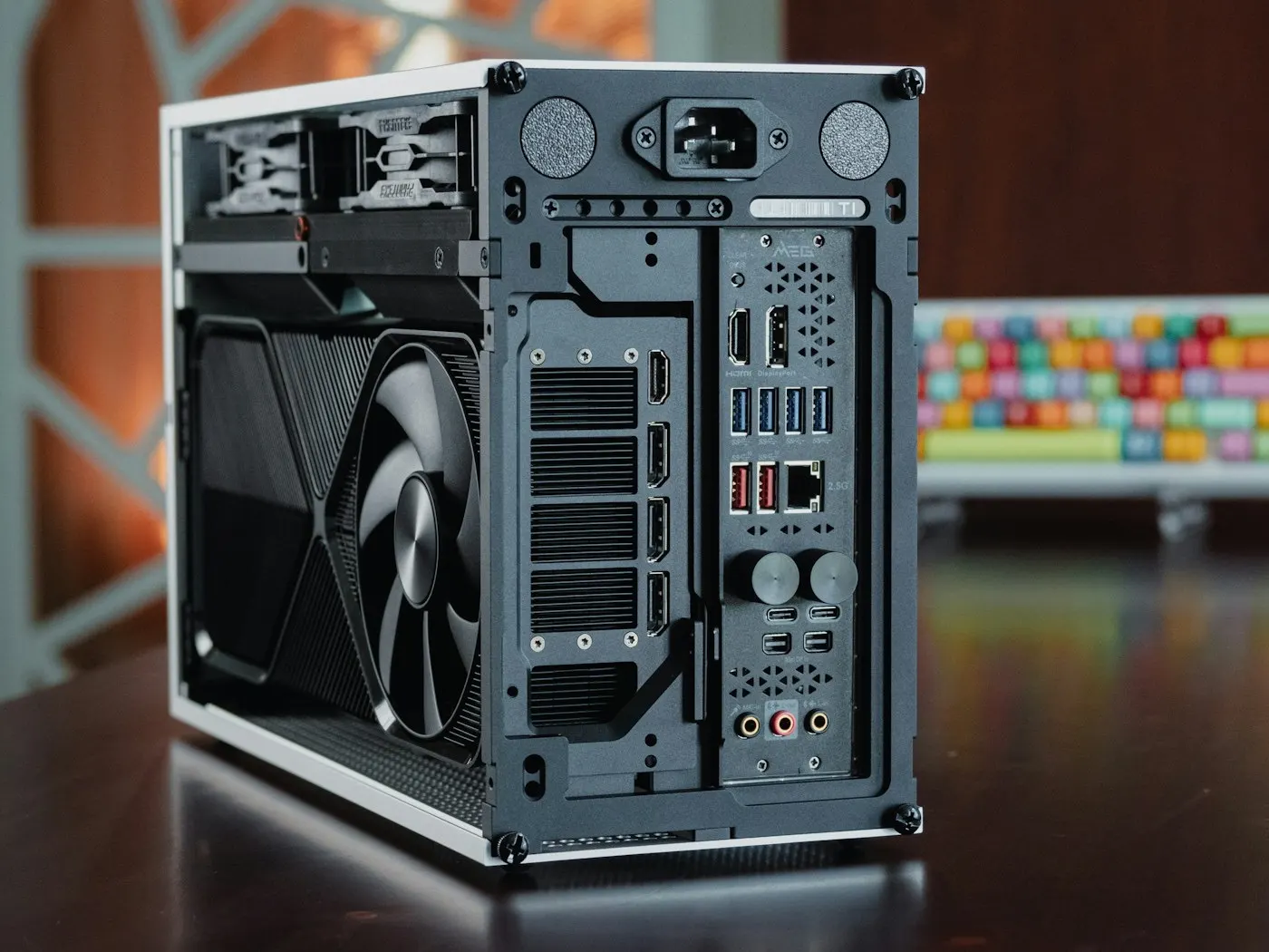 A compact desktop computer with a graphics card, on an office desk